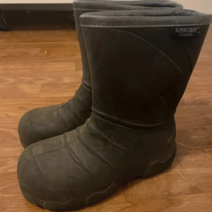 Svarta vinterstövlar från Kayoba - Svarta, robusta vinterstövlar från Kayoba Outdoor. Stövlarna har en hög modell med grov sula och är tillverkade i syntetmaterial, perfekta för kalla och blöta dagar. Diskret logga upptill och förstärkt tå för extra hållbarhet.
