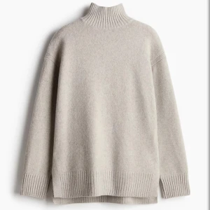 Beige polotröja  - Mysig beige polotröja med hög ribbad krage och avslappnad passform. Tröjan har långa ärmar och breda ribbade muddar vid ärmslut och nederkant. 