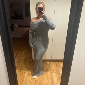 Stickad offshoulder maxiklänning - Grå stickad klänning med offshoulder och lång ärm. Klänningen har öppen rygg. Storlek s men passar mellan s-l