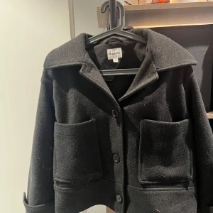 Svart ulljacka från Kappahl XS - Stilren svart jacka från Kappahl i ullblandning. Modellen är croppad med stora fickor framtill, klassisk krage och knäppning med tre knappar. Perfekt för dig som gillar en enkel men trendig look. Använd men i bra skick,pris kan diskuteras💕nypris 900kr