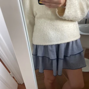 Blå och vit rutig kjol från Zara - Säljer en superfin blå och vit rutig kjol från Zara. Kjolen har en volangdetalj som gör den extra söt och perfekt för både vardag och fest. Den är i storlek M och passar perfekt till en stickad tröja eller en enkel topp. Perfekt för vår och sommar!passar mig som brukar ha xs!
