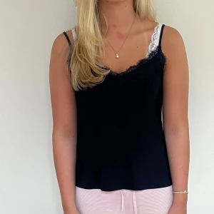 Mörkblå linnetopp med spetskant - Supersnygg mörkblå linnetopp med tunna axelband och dekorativ spets längs urringningen. På bilden ser tröjan lite svart ut men den är marinblå.