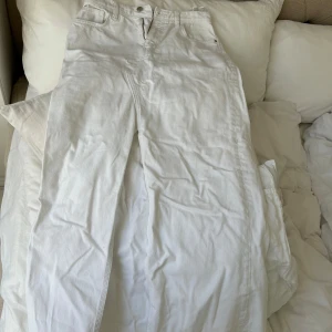 Vit jeans kjol med slits - Säljer en vit jeans kjol med slits. De har klassisk femficksdesign, bälteshällor och knappstängning. Kjolen är hög i midjan och har en riktigt clean look som passar till sneakers eller boots. Materialet är kraftigt denim i bomull.