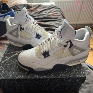 Nike Air Jordan 4, midnight navy  - Kvitto finns! Nike Air Jordan 4 i färgen White Oreo med vit ovandel i skinn, meshpaneler och detaljer i grått och marinblått. Sulan har stänk i grått och rött Jumpman-loggan undertill. Klassisk siluett med snörning och vadderad plös. Perfekta för dig som gillar retrostil och streetwear. Air Jordan 4 (midnight navy) i storlek 45, finns även kvitto! Box ingår