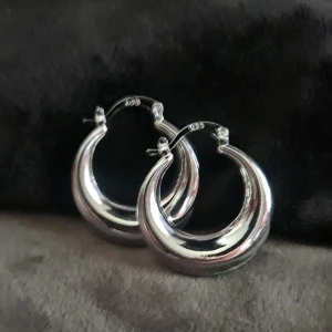 Chunky creoler i äkta silver 925 - Säljer ett par chunky creoler i äkta 925 silver. De är runda och tjocka med en blank, spegelblank finish som verkligen syns. Perfekta om du vill ha ett statement-smycke som ändå är klassiskt. Storleken är ca 3 cm i diameter.