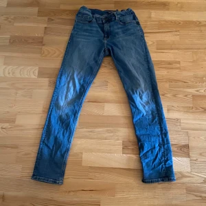 Blå jeans från Tommy Hilfiger -  Byxorna passar dom som är runt 176 cm långa .Säljer ett par klassiska blå jeans från Tommy Hilfiger. Byxorna har fem fickor, normal passform och raka ben. Perfekta för en avslappnad stil och har diskreta detaljer vid fickorna.