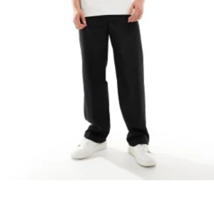 Svarta byxor från ASOS DESIGN - Svarta byxor från ASOS DESIGN med rak passform och elastisk midja. Klassisk och stilren look som passar till många tillfällen. Byxorna har en enkel design utan synliga detaljer och är tillverkade i ett mjukt material.