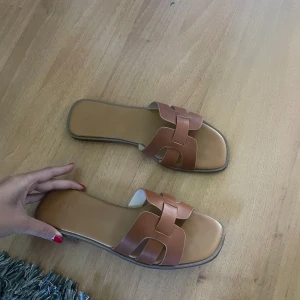 Bruna sandaler med flätad rem - Säljer ett par  bruna sandaler med platt sula och öppen tå. 