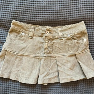 Manchesterkjol  - Intressekoll!! 🧡🧡Skitsnygg beige-grön minikjol i manchestertyg som är lågmidjad och köpt second hand. Kjolen är veckad och har normal passform, midjemått 42/43 cm och längd 31 cm. Skulle säga storlek S/M.  (Tryck ej på köp nu) 