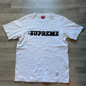 Vit t-shirt från Supreme med svart tryck - Vit t-shirt från Supreme med stort svart Supreme-tryck och stjärndetalj på bröstet. Vid fler funderingar kontakta mig 