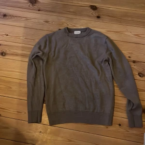 Grå tröja från John Henric - Säljer en stilren grå tröja från John Henric i storlek M. Tröjan har rund halsringning, långa ärmar och ribbade muddar vid ärmslut och nederkant. Perfekt för lager-på-lager och enkel att matcha med olika outfits. Stretchig men tight i storleken. Motsvarar snarare small i storleken. Gjord av 100 procent merinoull.
