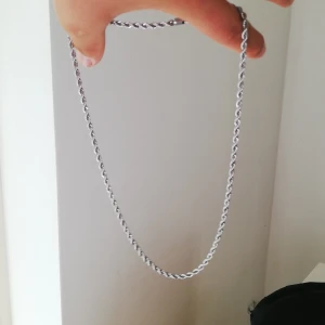 Silverfärgat halsband med tvinnad kedja - Säljer ett stilrent halsband i äkta silver med tvinnad kedja. Perfekt för dig som gillar enkla men snygga accessoarer. Passar till många olika stilar och är lätt att matcha med andra smycken. 