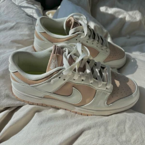 Nike Dunk Low i beige och vitt - Säljer ett par Nike Dunk Low sneakers i strl 40. Säljer dem då dem inte har kommit till användning, men de sitter förövrigt väldigt bra och är sköna. Är osäker på om jag har kvar original kartongen, men tror tyvärr inte det. Priset kan diskuteras💞