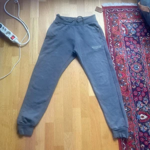 Grå mjukisbyxor från McKenzie - Grå mjukisbyxor från McKenzie med resår i midjan och muddar vid bensluten. Byxorna har en enkel design med diskret logga på ena benet och är perfekta för en avslappnad stil.