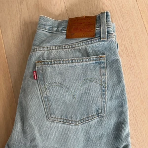 Ljusblå Levis 501 jeans - Säljer ett par klassiska ljusblå Levis 501 jeans med raka ben och knappgylf. Jeansen har fyra fickor och den ikoniska Levis-lappen bak i midjan. Perfekta för en avslappnad och tidlös stil. W28 L30 
