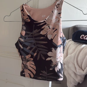 Blommig linnetopp från H&M - Säljer ett snygg träningslinne från H&M med blommigt mönster i rosa och beige toner mot svart bakgrund. 
