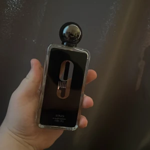 9pm Eau de Parfum från Afnan - Säljer en stilren parfymflaska från Afnan, modellen 9pm. Flaskan är rektangulär med svart etikett och stor siffra 9 i silver. Kulan på korken är svart och flaskan är genomskinlig med ljusgul vätska. Perfekt för dig som gillar eleganta dofter.100 ml