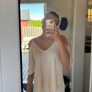 Vit offshoulder topp - Säljer en vit, lös och flowy topp med offshoulder-design och trekvartsärm. Toppen har en djup v-ringning både fram och bak och är perfekt för en avslappnad och stilren look.