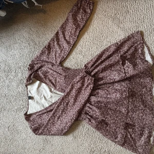 Brun blommig klänning - Säljer en ljusbrun med små vita blommor och lång ärm. Klänningen har v-ringning. Perfekt för vår och höst! 