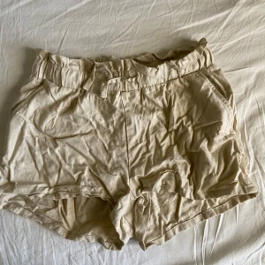 Beiga shorts från Lindex i linneblandning - Säljer ett par beiga shorts från Lindex i en skön blandning av linne och viskos. De har resår i midjan och ett löst, avslappnat snitt. Perfekta för varma dagar och riktigt bekväma att bära.