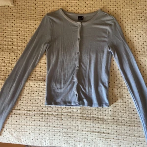 Ljusblå kofta från Gina Tricot - Säljer en ljusblå, tunn och mjuk kofta från Gina Tricot i storlek S. Koftan har långa ärmar och knäpps framtill med små knappar. Koftan har knappt använts och är i mycket bra skick.