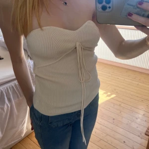 Beige/Vit ribbad tubtopp med knyt - Tubtopp från & otherstories med detalj med snörning som kan bäras på olika sätt exempelvis knyt framtill eller runt halsen. 