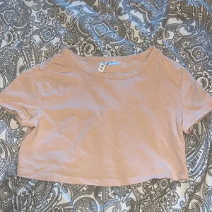 Rosa beige croppad t-shirt från H&M Divided - Säljer en enkel och stilren rosa beige croppad t-shirt från H&M Divided. T-shirten har korta ärmar och rund halsringning, perfekt att matcha med jeans eller kjol. Fick den av min faster efter jag hade frågat om hon hade ett linne jag kunde få🥲