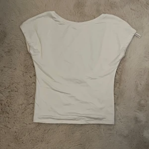 Vit croppad topp med öppen rygg - Säljer en vit croppad topp med korta ärmar och en djup, öppen rygg. Perfekt för dig som vill ha en enkel men snygg topp till sommaren. Tunt och mjukt material som känns skönt mot huden.