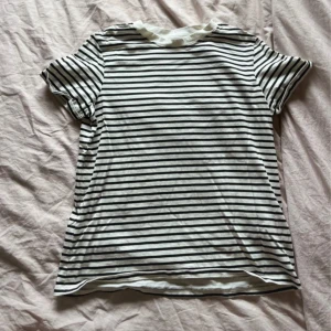 Randig t-shirt från new yorker - Vit t-shirt med svarta horisontella ränder. Klassisk rund halsringning och korta ärmar. Skön bomullskänsla och regular fit. Köptes för ca 2 månader sen men aldrig kommit till användning! 