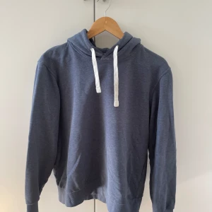 Blå hoodie från Jack & Jones - Säljer en stilren blå hoodie från Jack & Jones Originals. Tröjan har huva med vita snören och ribbade muddar vid ärmslut och nederkant. Perfekt för en avslappnad look.