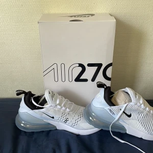 Nike Air Max 270 vita sneakers - Säljer ett par helt nya Nike Air Max 270 i vitt med svarta detaljer och stor synlig luftbubbla i hälen. Ovandelen är i mesh för bra ventilation och skon har en sportig, modern look. Perfekta för dig som gillar stilrena sneakers. Hör av dig vid frågor, Pris kan diskuteras😉