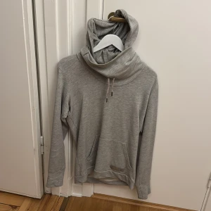 Grå hoodie från Diesel - Säljer en grå hoodie från Diesel med hög krage och luva. Tröjan har känguruficka framtill och dragsko i halsen. Perfekt för dig som gillar en stilren och enkel look. Storlek M.