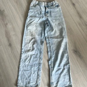 Ljusblå jeansbyxor från Lindex - Säljer ett par ljusblå jeansbyxor från Lindex med raka ben och klassisk femficksdesign. Byxorna har normal passform och är tillverkade i bomull. Perfekta för en avslappnad stil.