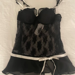 Vintage 00s spetsklänning/topp  - Elegant svart spetsklänning från La Senza med vita detaljer och knytband i midjan. Klänningen har en vacker spetsdesign och justerbara axelband. Perfekt för en speciell kväll. S/M/XS