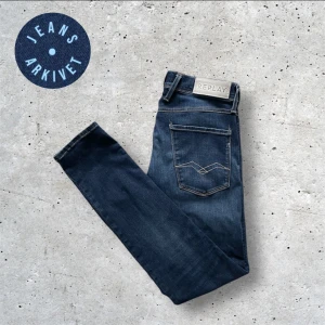 Blå jeans från Replay - Snygga blå jeans från Replay i modellen Anbass. De har en klassisk femficksdesign med knappgylf och bälteshällor. Perfekta för en stilren look. Skriv vid funderingar💬