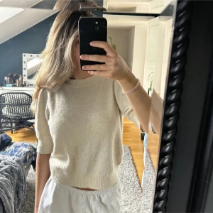 Beige stickad tröja - Säljer en mysig beige stickad tröja med trekvartsärm. Perfekt för en avslappnad stil och passar bra till både jeans och kjol. Tröjan har en enkel och stilren design. Finns en liten fläck på denna men inte nått som syns mycket!