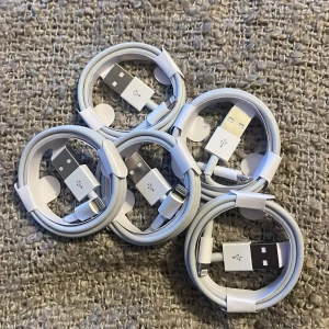 Vita USB-laddningskablar - Säljer fem vita USB-laddningskablar med Lightning-kontakt. Perfekta för att ladda och synka dina Apple-enheter. Kablarna är praktiskt ihoprullade och lätta att ta med sig.