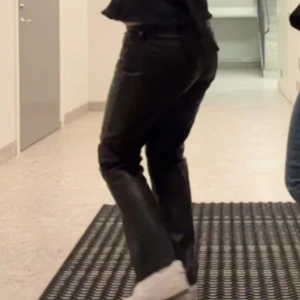Svarta skinnbyxor - Snygga svarta skinnbyxor med en bootcut passform. Perfekta för en trendig look och kan enkelt matchas med olika toppar. Byxorna har en stilren design utan extra detaljer.