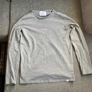 Grå långärmad tröja från Les Deux - Säljer en stilren grå långärmad tröja från Les Deux. Tröjan har en rund halsringning och är tillverkad i mjukt bomullsmaterial. 