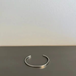 Enkel silverfärgad armring - Säljer en stilren och minimalistisk armring i silverfärg. Perfekt för att komplettera din outfit med en subtil touch av elegans. Passar både till vardag och fest.