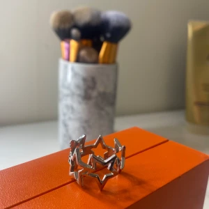 Silverring med stjärndesign - Snygg silverring med stjärnformad design. Perfekt för att ge en unik touch till din stil. Ringen har en öppen design med flera stjärnor som ger ett modernt och trendigt utseende. Super snygg nu till sommaren. Färgen är fortfarande fin och det finns Inge tecken på att den börjar tappa färg. Kommer inte ihåg varifrån jag köpt den, den är perfekt och dessutom justerbar och passar alla🥰💞