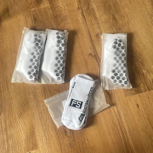  FS skillsocks - Säljer vita strumpor från FS med svarta grepp på undersidan. Perfekta för träning eller inomhusaktiviteter där extra grepp behövs. Strumporna är förpackade i plast och har en stilren design med FS-loggan. En för 100- alla 4a för 300