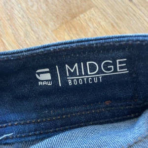 Blå bootcut jeans från G-Star RAW - Mörkblå jeans från G-star. Jätte fina detaljer på rumpan. Uppsprättade längst ner men inget som syns