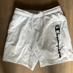 Vita shorts från Champion - Snygga vita shorts från Champion med elastisk midja och snörning. Perfekta för en avslappnad stil. Champion-loggan i svart på sidan ger en cool touch.