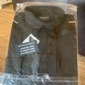 Svart skjorta från Harvest - Snygg svart skjorta från Harvest med klassisk krage och knappar framtill. Perfekt för en stilren look. Aldrig använd.