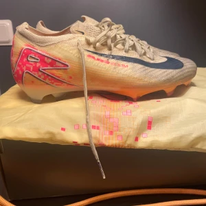  fotbollsskor från Nike - Snygga fotbollsskor från Nike i gula,röda och svarta detaljer. Skorna har en rund tå och snörning för optimal passform. Perfekta för fotbollsplanen med sin lätta och smidiga design.Jag har kvitto,originalbox och påse.