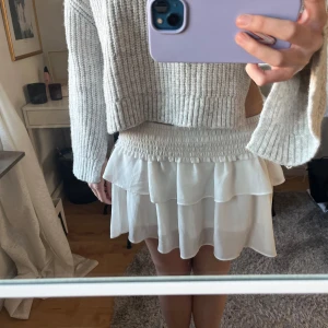 Vit volangkjol - Söt vit volangkjol och ribbat band vid midjan. Perfekt för sommarens varma dagar. 