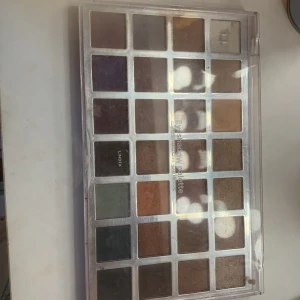 Ögonskuggspalett från Lindex - Stor ögonskuggspalett från Lindex med 28 olika nyanser. Paletten innehåller både matta och skimrande färger i jordnära toner som brunt, beige, och grått samt några färgglada inslag som lila och grönt. Perfekt för att skapa både vardagliga och festliga looks.