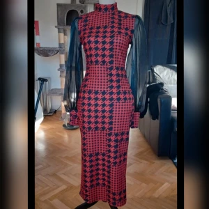 Röd och svart klänning från Shein - Snygg röd och svart klänning från Shein med ett iögonfallande rutigt mönster. Klänningen har långa, transparenta ärmar och en hög krage. Perfekt för en elegant look.