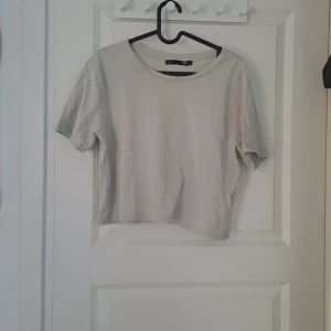 Beige croppad t-shirt från 157 - Säljer en stilren beige croppad t-shirt från 157. Den har en rund halsringning och korta ärmar, perfekt för en avslappnad look. Passar bra till jeans eller kjol för en enkel och snygg outfit.